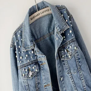 Close-up view of women's short denim jacket featuring elegant white pearl embellishments