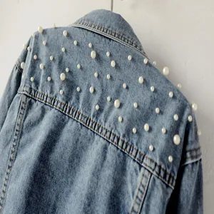 Detail view of a light blue denim jacket featuring elegant white pearl embellishments
