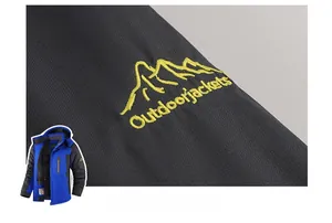 Close-up detail of yellow embroidered mountain logo and text on outdoor jacket sleeve