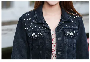 Close-up of women's dark denim jacket featuring elegant white pearl bead embellishments