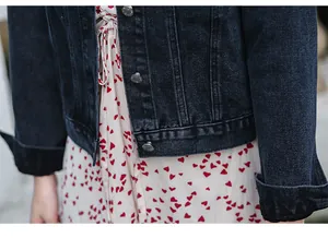 Close-up detail of dark blue women's denim jacket with metal buttons over a heart dress