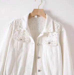 Close-up of white cropped denim jacket featuring delicate pearl and rhinestone embellishments