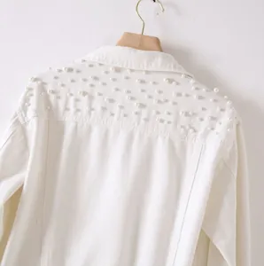Detail shot of a white denim jacket featuring elegant pearl bead embellishments on back