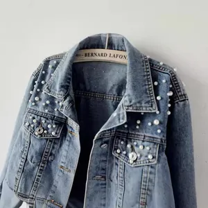 Close-up of blue denim jacket for women featuring pearl bead embellishments and cropped fit.