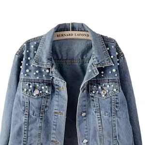 Detailed view of white pearls and rhinestone embellishments on a classic blue denim jacket