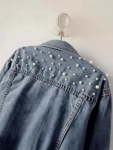 Stylish women's cropped denim jacket with elegant white pearl embellishments on shoulders