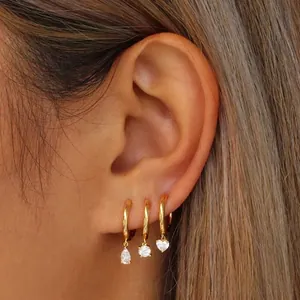Set of three minimalist gold hoop earrings with sparkling zircon heart and drop pendants