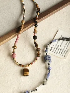Gros plan d'un collier fait main avec des perles naturelles en œil de tigre et agate