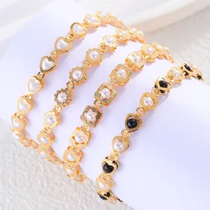 Close-up of gold bracelets featuring heart and flower designs with white and black pearls