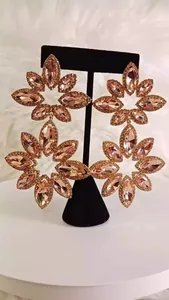 Exaggerated luxury pink crystal flower dangle earrings shown on a black jewelry stand