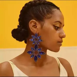 Detailed view of oversized blue crystal flower dangle earrings with sparkling rhinestones