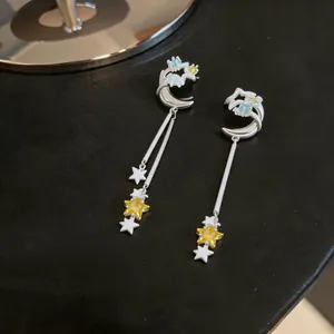 Close-up of elegant star and moon dangle ear clips with yellow zircon and tassels
