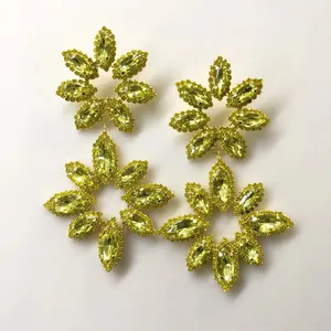 Detailed view of oversized yellow crystal flower dangle earrings with rhinestones.