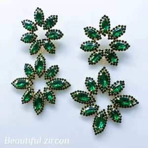 Close-up detail of luxurious emerald green crystal flower drop earrings for women.