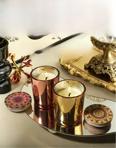 Close-up view of starry metallic scented candle cups with ornate lids displayed on a mirror.