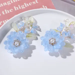 Close-up van handgemaakte blauwe kristallen bloem haaraccessoire met groene bladeren