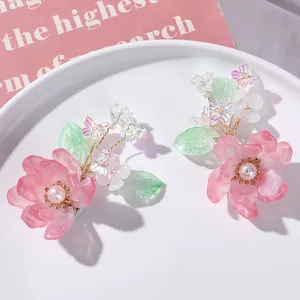 Detailopname van een handgemaakt roze kristallen bloemaccessoire met groene bladeren.