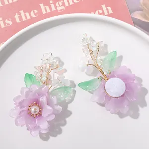 Gedetailleerd overzicht van handgemaakte kristallen paarse bloem en groen blad DIY sieraden