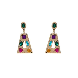 Vue macro de boucles d'oreilles géométriques en or avec des strass multicolores de diverses formes