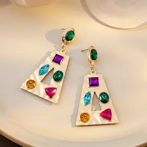 Gros plan de boucles d'oreilles dorées géométriques avec strass multicolores