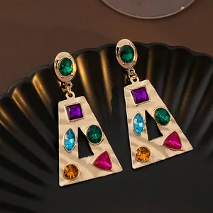 Gros plan de boucles d'oreilles pendantes géométriques dorées avec strass multicolores