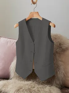 Close-up detail of women's charcoal grey suit vest hanging on a wooden hanger aesthetic view.