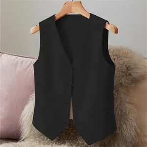 Classic black women's suit vest with V-neck hanging on a wooden hanger in cozy decor.