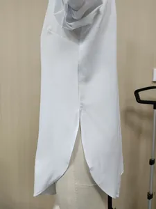 Detailed macro view of white long sleeve shirt showing side slit and curved hem on mannequin