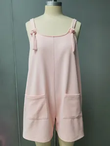 Macro view of solid pink textured romper featuring tie-knot straps and dual front pockets