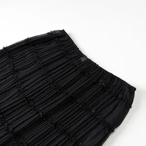 Primo piano di gonna lunga plissettata nera con trama arricciata ed elastico in vita