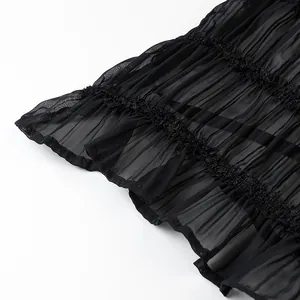 Primo piano macro della trama del tessuto chiffon plissettato nero con bordo a balze