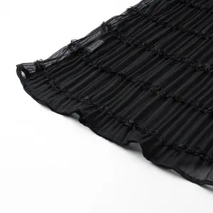 Primo piano del tessuto a pieghe nero con elegante pizzo e bordi a balze delicati