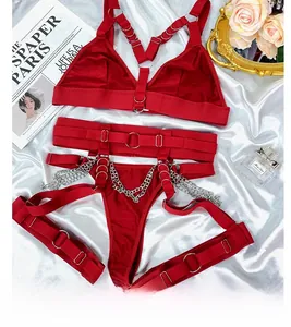 Dettaglio di lingerie bondage rossa con catene e anelli su sfondo di raso bianco
