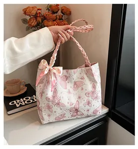 Dichtbij van een roze vlinderprint tote tas met elegante gevlochten handvatten en een strik
