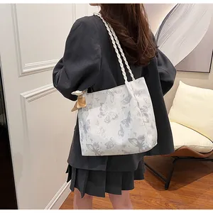 Model draagt een grote witte draagtas met elegante blauwe vlinderprints erop uit