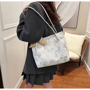 Gedetailleerd overzicht van de witte vlinder tote bag met gevlochten riemen op een model
