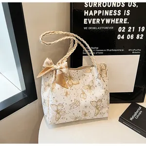 Detail van witte tote bag met vlinderprint, gevlochten handvatten en decoratieve strik