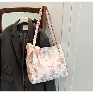 Detailweergave van de witte draagtas met roze vlinderpatronen en een gevlochten riem