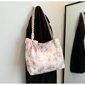 Detailopname van draagtas met vlinderprint, roze gevlochten riem en strikdecoratie.