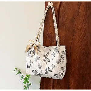 Detailweergave van een witte draagtas met vlinderprints hangend aan een houten deur