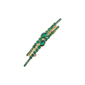 Detailed close-up of elegant gold hair clip with sparkling emerald green rhinestones