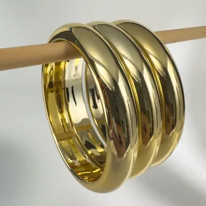 Macro detail of three glossy polished gold metal chunky bangles for minimalist style