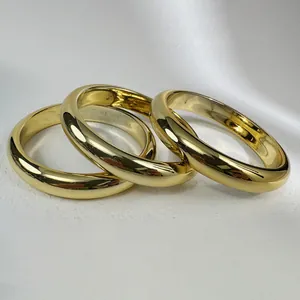 Detailed view of three stacked minimalist polished gold-colored bangles with a metallic luster.