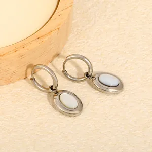 Detailed macro shot of elegant silver-tone hoop earrings with white oval shell pendants
