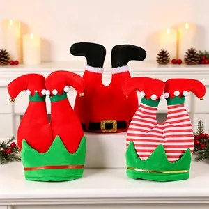 Trois chapeaux de fête de Noël en forme de jambes d'elfe et de Père Noël sur une cheminée.