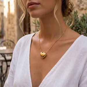 Detailed view of a polished 18k gold plated 3D heart pendant necklace on a model.