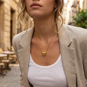 Detailed shot of a gold-plated heart pendant necklace worn on a linen blazer outfit