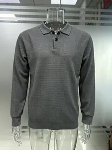 Detailed texture of men's grey waffle knit long-sleeve polo sweater.