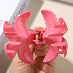 Makrodetail einer rosa Frangipani-Blütenhaarklammer mit einer goldenen Metallfeder.