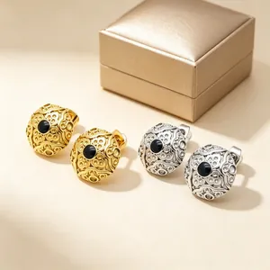 Macro view of vintage stainless steel stud earrings with intricate embossed floral patterns